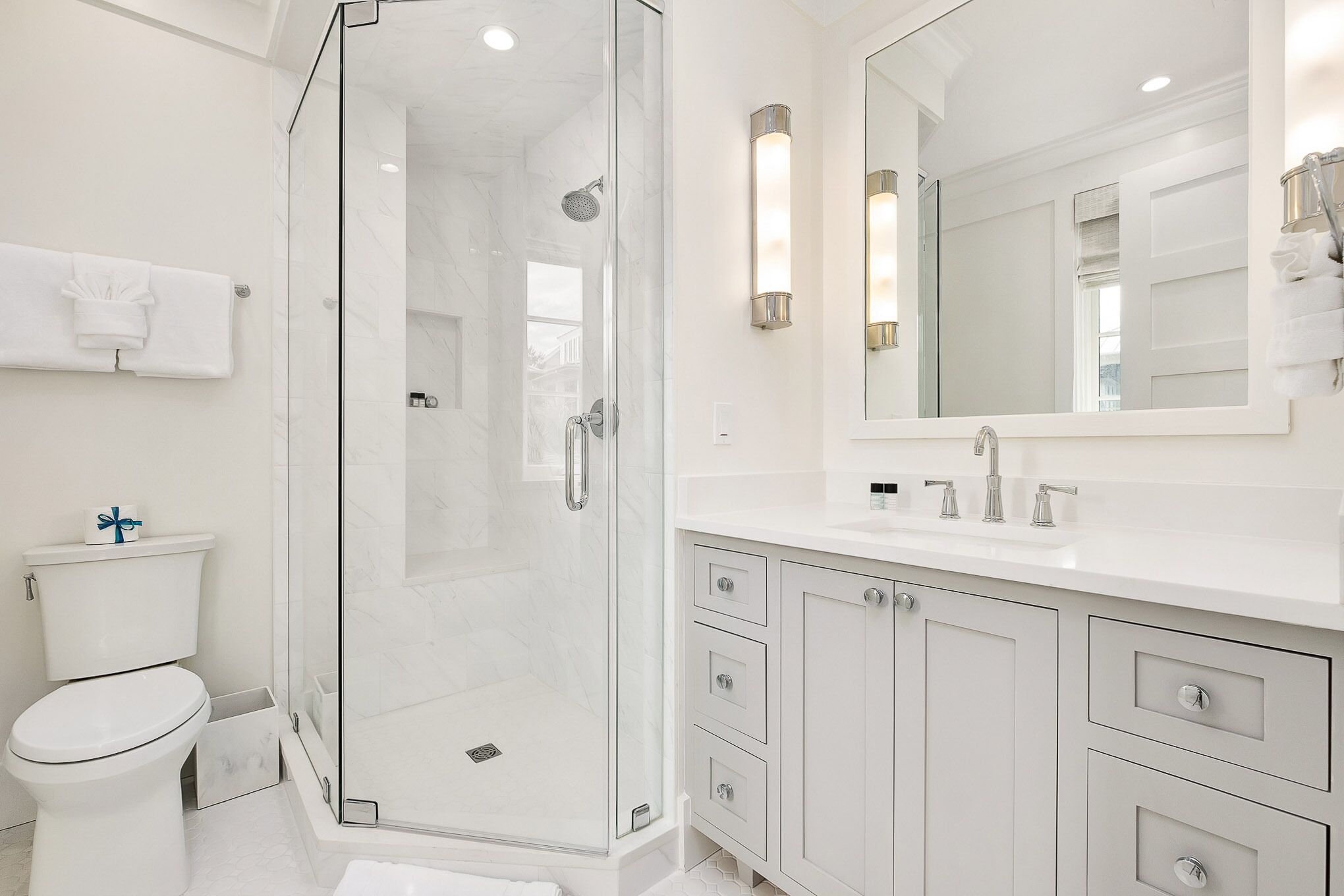 A modern bathroom with a glass-enclosed shower, a white toilet, and a vanity with drawers and a mirror.