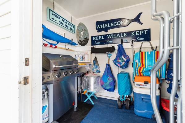 A compact kitchen with a stove, a small refrigerator, and a sink. There are various bags and a blue cooler on the floor.