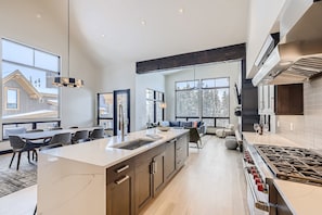 A modern kitchen with a large island, built-in appliances, and large windows. - Golden Foxes | Peak 8 Location! | Hot Tub! (Breckenridge)