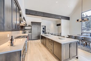A modern kitchen with a large island, stainless steel appliances, and a dining area with a view.
