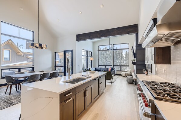 A modern kitchen with a large island, built-in appliances, and large windows.