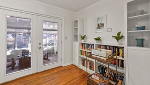 A room with a wooden floor, white walls, and a bookshelf filled with books. - Artist's Cottage - Comfortable Pet friendly home 1 mile from the beach! (St Simons Island)