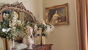A room with a wooden dresser, a large ornate mirror, a vase with flowers, a framed painting, and a chair. - The Beaumont House (Natchez)