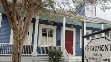 A historic house with a blue exterior, white trim, and a red door. A sign indicates it was built by Andrew Brown in 1830.