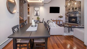 A modern living room with a fireplace, a dining area with a long table and chairs, and a seating area with a sofa and coffee table. - Vail Point #7 4 Bedroom Townhouse by RedAwning (Vail)