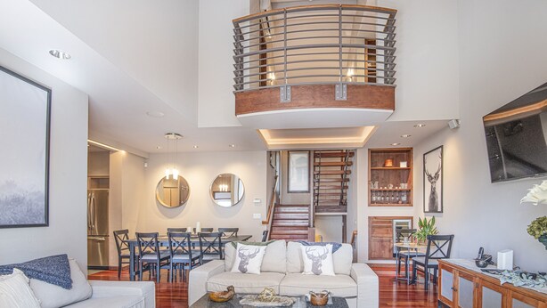 A spacious living area with a high ceiling, a central staircase, and a dining area. - Vail Point #7 4 Bedroom Townhouse by RedAwning (Vail)