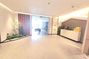 Um saguão de hotel com balcão de recepção, área verde e vista para a sala de jantar.