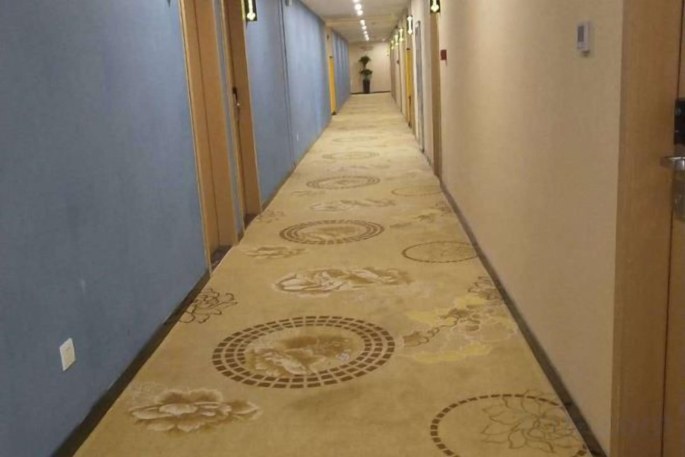 Un pasillo de hotel con pisos alfombrados y puertas a ambos lados.