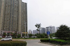 A high-rise building with a clear sky, a roundabout with a blue sign, and a white car parked nearby. - Citi Home Hotel (Taohua Town Government) (Feixi)
