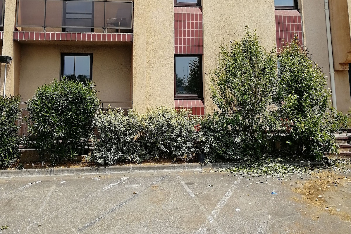 Un edificio de varios pisos con balcones, estacionamiento y zonas verdes aledañas.