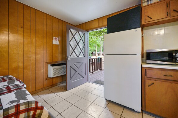 A compact kitchen with a refrigerator, microwave, and wooden cabinets.