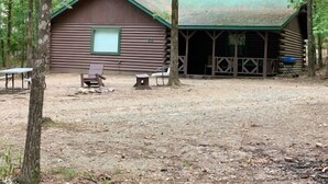 A rustic log cabin with a green roof, a window, and a porch area.