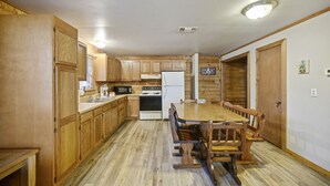 A kitchen with wooden cabinets, a dining table with chairs, a refrigerator, and a microwave.
