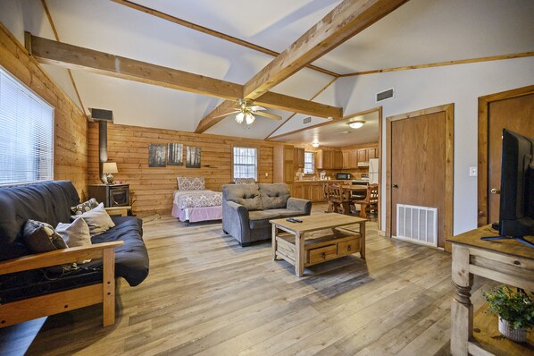 A spacious living room with a wooden ceiling, a sofa, a loveseat, and a coffee table.