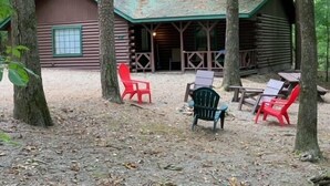 A rustic log cabin with a porch and outdoor seating area.