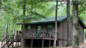 Een chalet met een houten terras en een trap naar een veranda.
