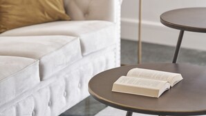 A modern living room with a white sofa, a round table with an open book, and a potted plant. - Chic n Bright 3 Bd Apt with Hilton View (Athens)