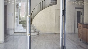 A modern interior with a curved staircase, a glass door entrance, and a marble floor. - Chic n Bright 3 Bd Apt with Hilton View (Athens)