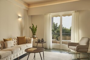 A living room with a sofa, armchair, coffee table, and a potted plant.