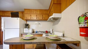 Eine Küche mit Holzschränken, einem weißen Kühlschrank, einer Mikrowelle, einem Herd und einem Feuerlöscher.