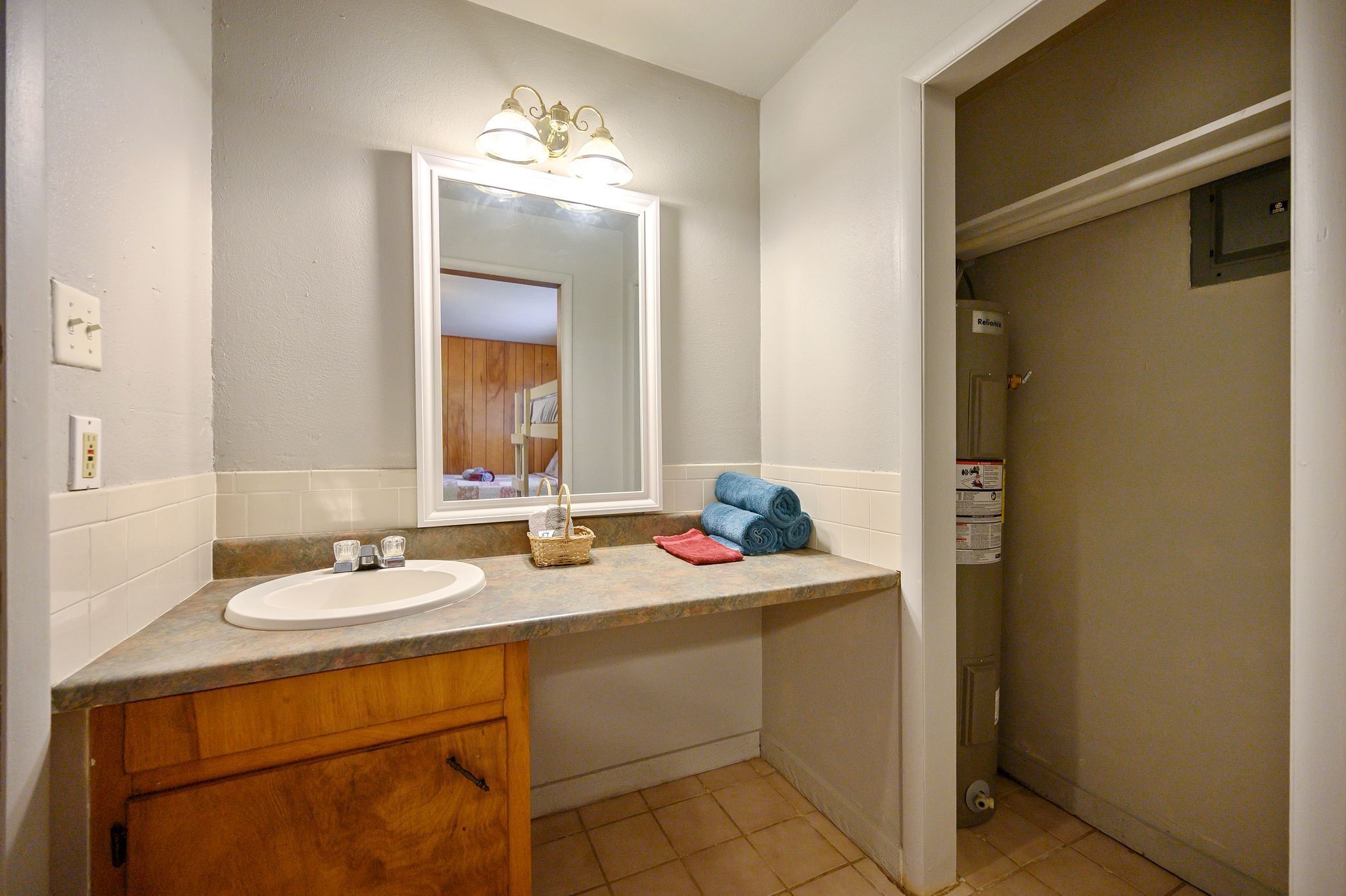 A bathroom with a sink, mirror, towel rack, and shower stall.