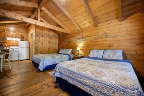 Quarto estilo cabana com duas camas, cozinha compacta e paredes de madeira.