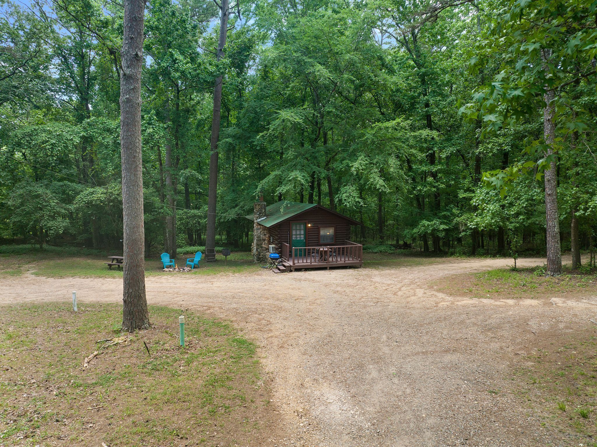 A rustic cabin with a porch, surrounded by dense forest.