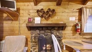 Una habitación acogedora con chimenea de piedra, un repisa de madera y una decoración con forma de corazón encima.