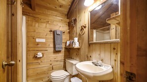 A wooden cabin bathroom with a toilet, sink, and a towel hanging on the wall. - Tiddly Winks | Honeymoon Cabin | Fireplace & Near Beavers Bend (Broken Bow)