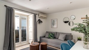 Un salon moderne avec un canapé gris, une table basse ronde en bois et un vase en verre contenant des plantes.