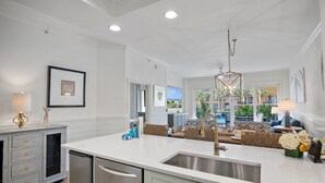 Cocina moderna con una isla grande, electrodomésticos de acero inoxidable y vista al área de la piscina exterior.