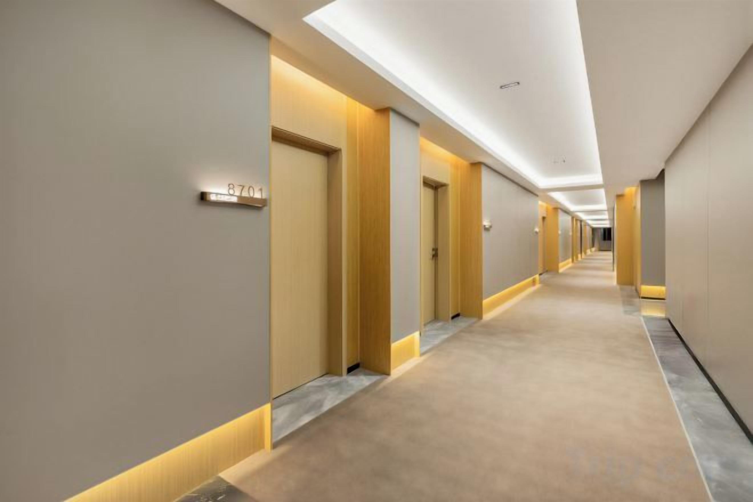Passadís d'hotel amb portes, sòl amb moqueta i il·luminació empotrada.