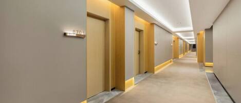 A hotel corridor with doors, a carpeted floor, and recessed lighting.