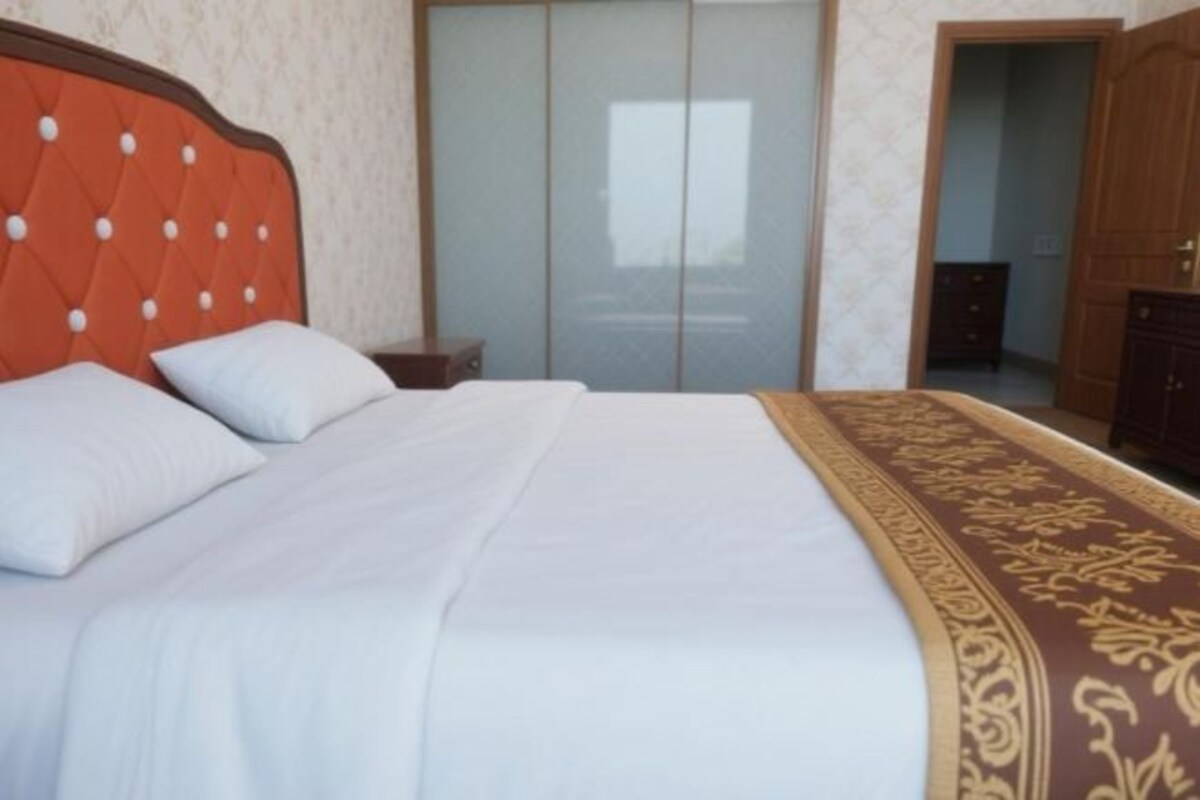 A bed with a headboard, white bedding, and a decorative throw.