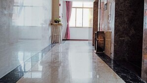 A hotel lobby with a polished marble floor, a wooden reception desk, and a large window with a pink curtain. - Guangzhou New Modern Hotel (Shiling lisha squar) (Guangzhou)
