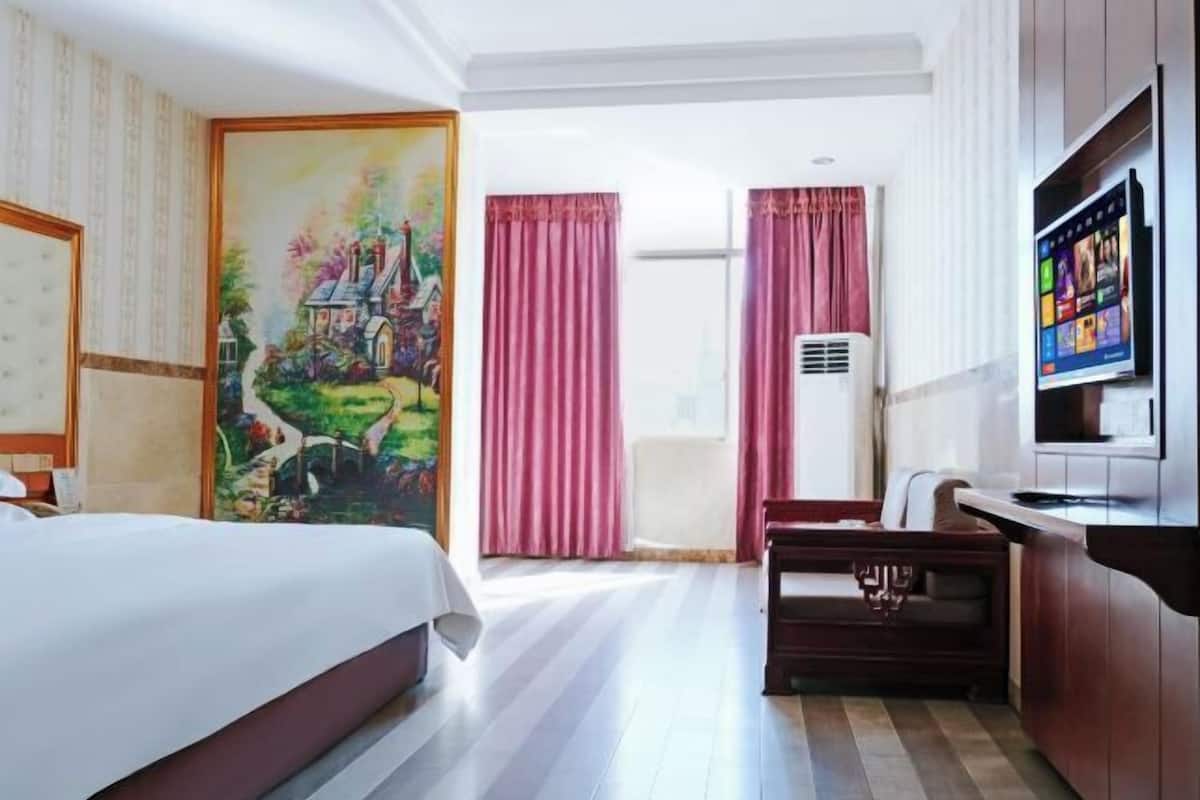 Una habitació d'hotel amb un llit, una taula de treball, una cadira, una televisió i un quadre a la paret.
