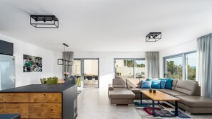 A modern apartment with a kitchen, dining area, and living room. There are large windows, a sofa, and a coffee table. - Seaview Villa Big Blue with 32sqm heated pool, 4 bedrooms (Podstrana)