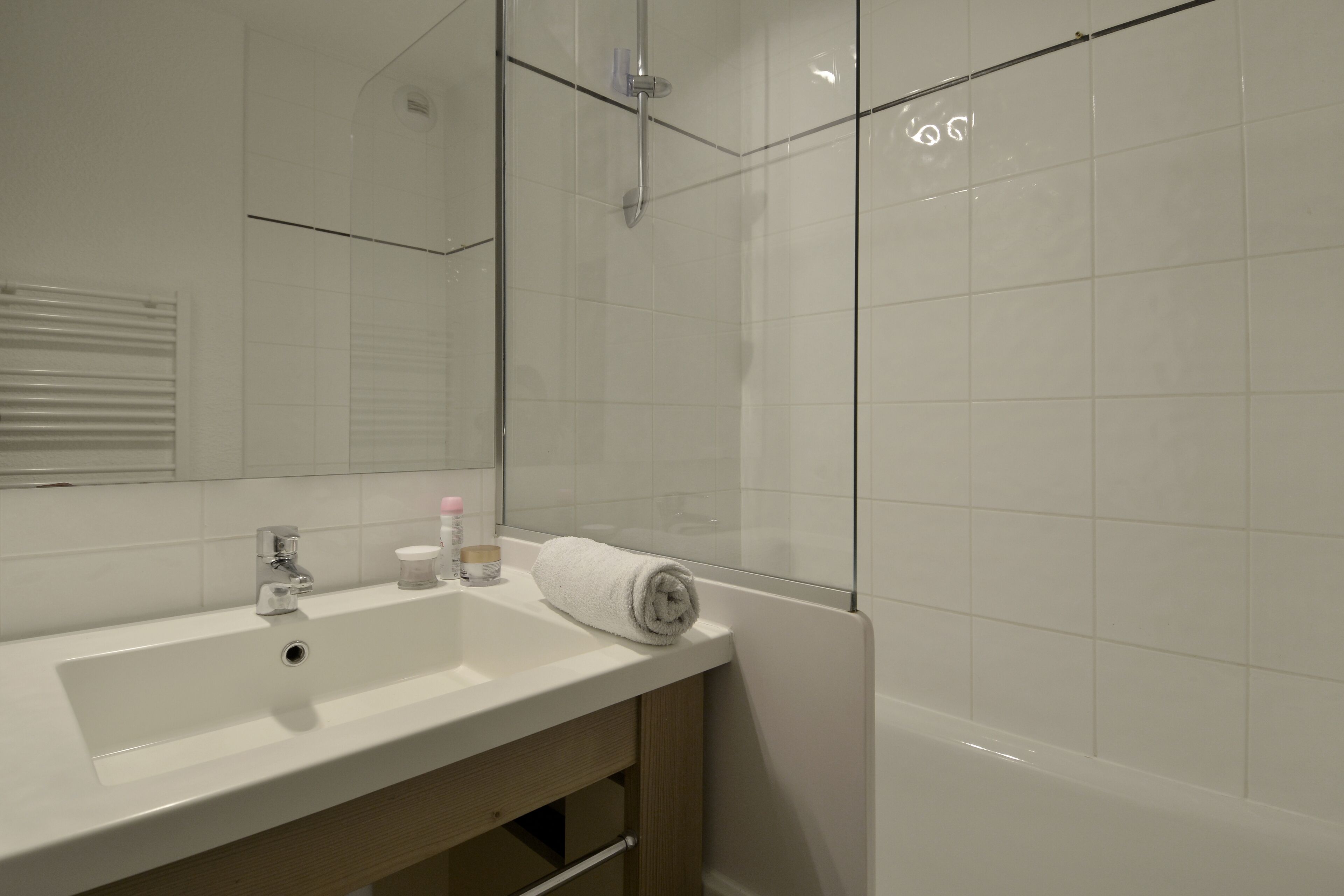 Une salle de bain avec un lavabo blanc, un miroir, une cabine de douche en verre et une baignoire blanche.