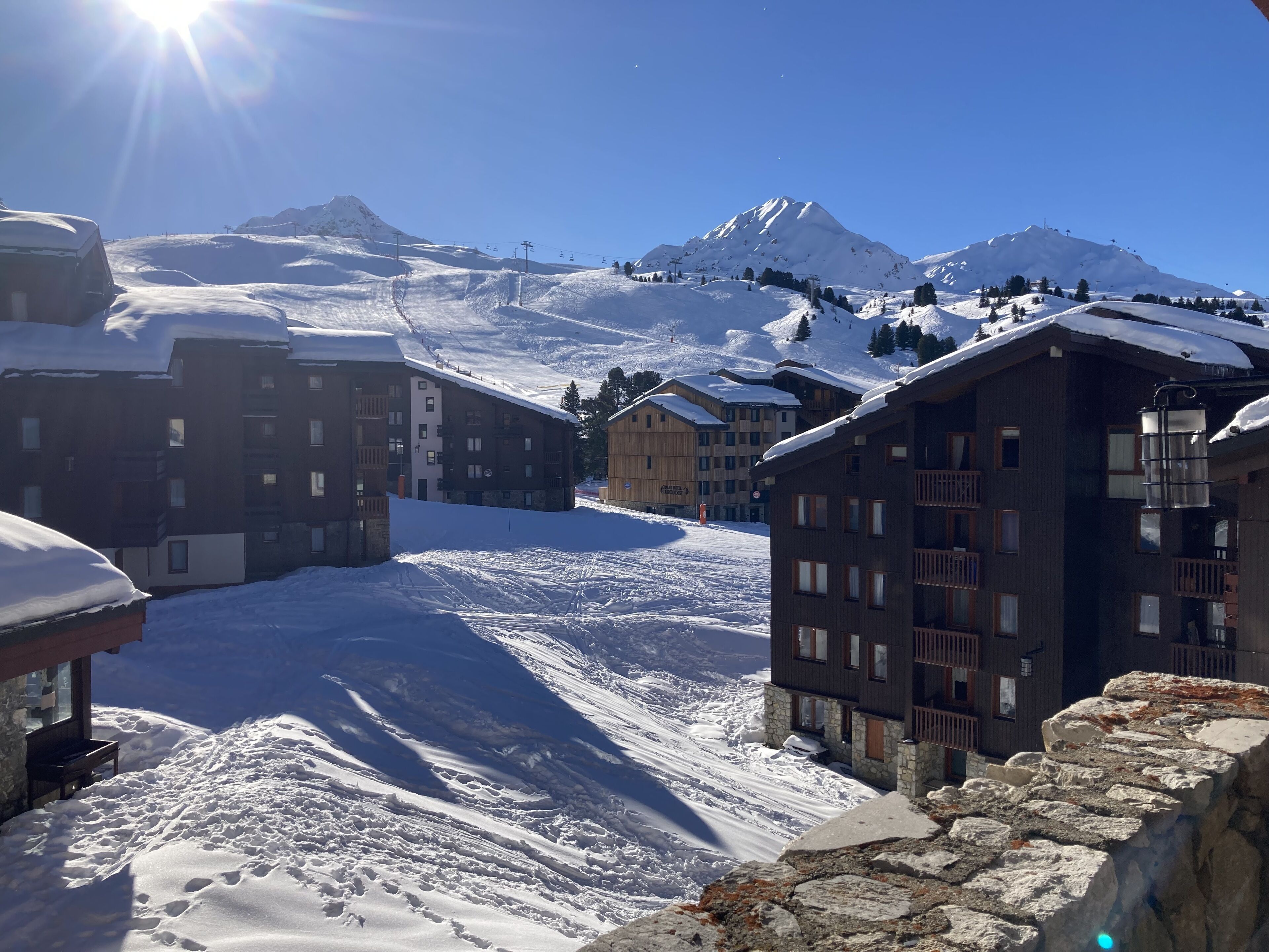 Een besneeuwde bergstad met moderne gebouwen, skipistes en een heldere lucht.