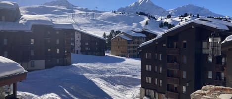 Een besneeuwde bergstad met moderne gebouwen, skipistes en een heldere lucht.