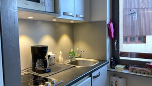 A compact kitchen with a microwave, coffee maker, and sink.