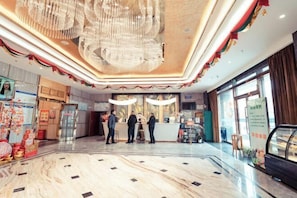 A hotel lobby with a marble floor, a chandelier, and a reception desk. - Henglong International Hotel (Karamay)