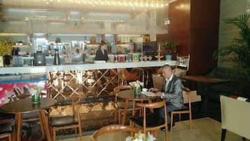 Een restaurant met een bar, zitplaatsen en een balie waar personeel bedient.