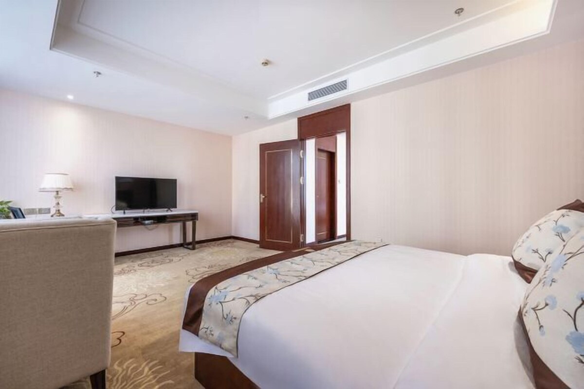 Una habitación de hotel con una cama, un escritorio, un televisor y una puerta.