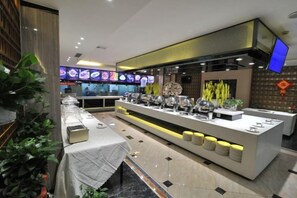 Un restaurante con una barra larga, varias estaciones de comida y un diseño de interiores moderno.
