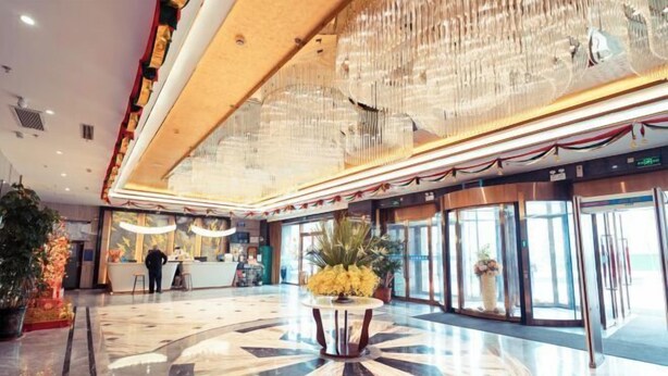 A spacious lobby with a large, ornate chandelier, a reception desk, and a central decorative table. - Henglong International Hotel (Karamay)