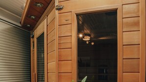 A sauna room with wooden walls, a potted plant, towels, and a sauna brochure. - Romantic Getaway with Sauna, fireplace and great seal watching (Oakley)