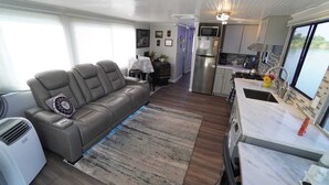 A compact living space with a sofa, a kitchen area, and a dining table. - Romantic Getaway with Sauna, fireplace and great seal watching (Oakley)