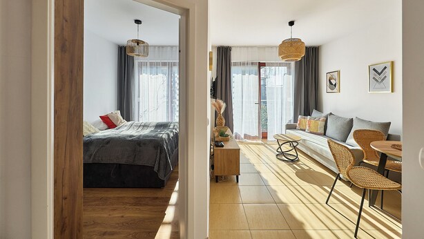 Ein modernes Schlafzimmer mit Bett, Nachttisch und Blick auf den Wohnbereich.