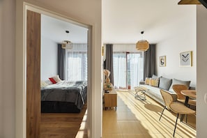 A modern bedroom with a bed, bedside table, and a view of the living area.